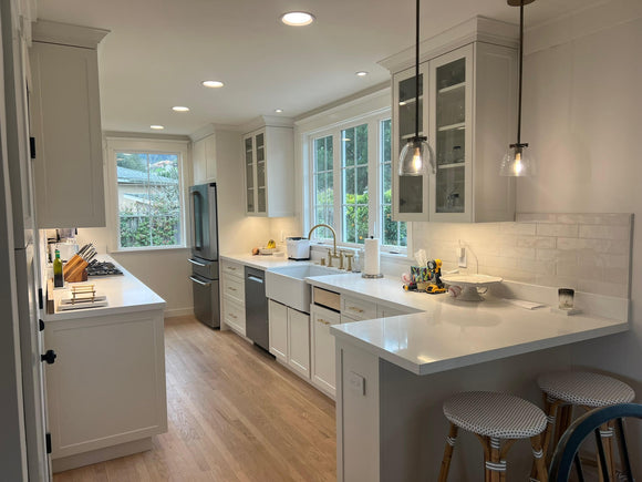 Modern kitchen with white cabinets, stainless steel appliances, and a breakfast bar.