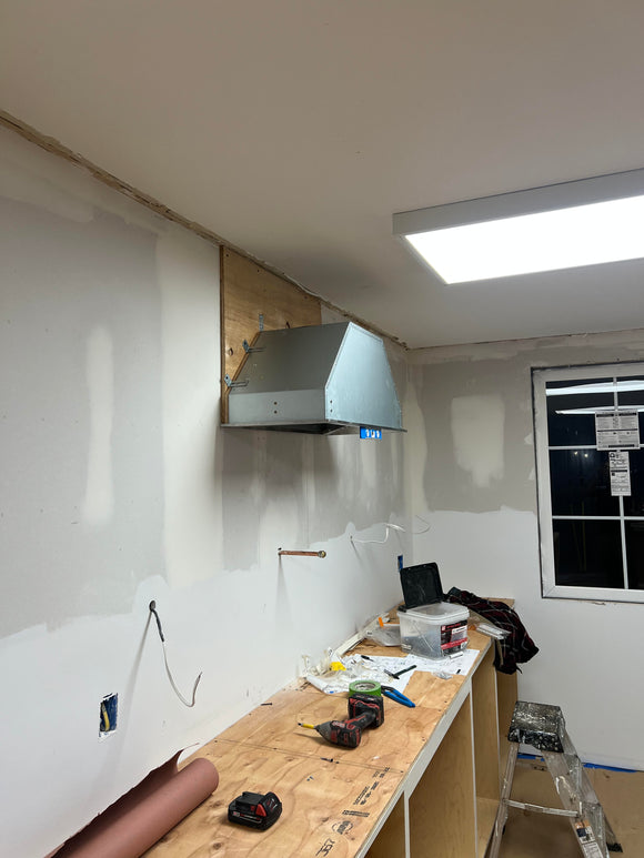 Under construction kitchen with exposed pipes and unfinished walls.